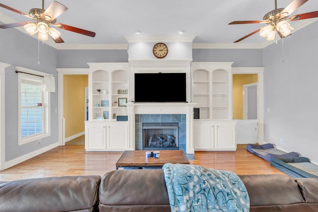 living room with a fireplace, light wood-style flooring, baseboards, and a ceiling fan
