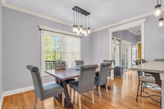 dining area featuring light wood finished floors, ornamental molding, and plenty of natural light