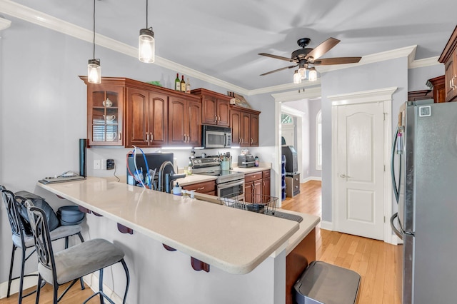 kitchen featuring light countertops, appliances with stainless steel finishes, a breakfast bar, a ceiling fan, and a peninsula