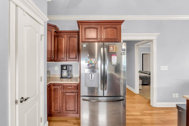 kitchen with stainless steel fridge with ice dispenser, baseboards, light countertops, crown molding, and light wood-style floors