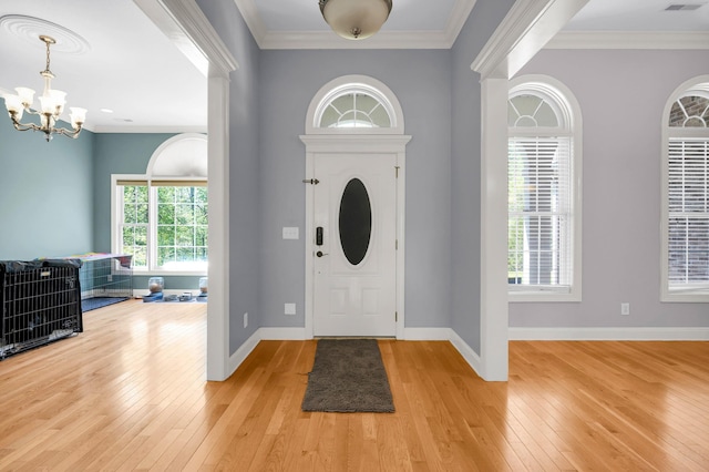 foyer entrance featuring a chandelier, light wood-type flooring, baseboards, and ornamental molding