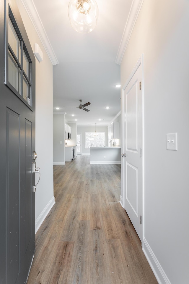 hall featuring wood finished floors, baseboards, ornamental molding, and recessed lighting