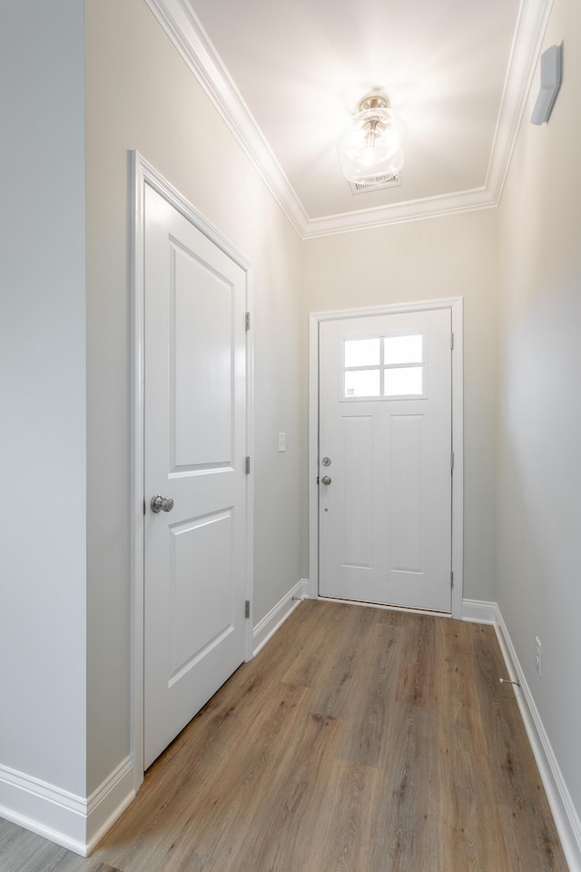 entryway with crown molding, wood finished floors, and baseboards