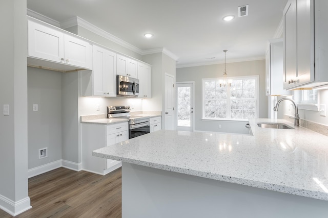 kitchen with a peninsula, white cabinets, light stone counters, a sink, and stainless steel appliances
