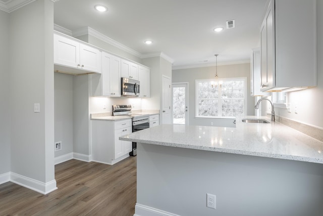 kitchen with a sink, white cabinets, appliances with stainless steel finishes, and a peninsula