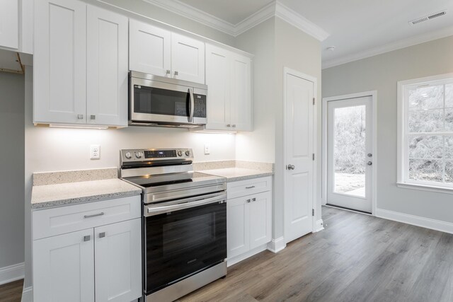 kitchen with ornamental molding, light wood-style flooring, white cabinets, visible vents, and stainless steel appliances