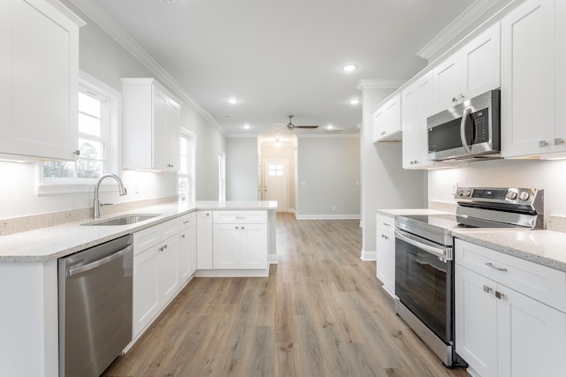 kitchen featuring a sink, ceiling fan, appliances with stainless steel finishes, a peninsula, and crown molding