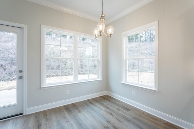 unfurnished dining area featuring light wood-style floors, an inviting chandelier, baseboards, and ornamental molding