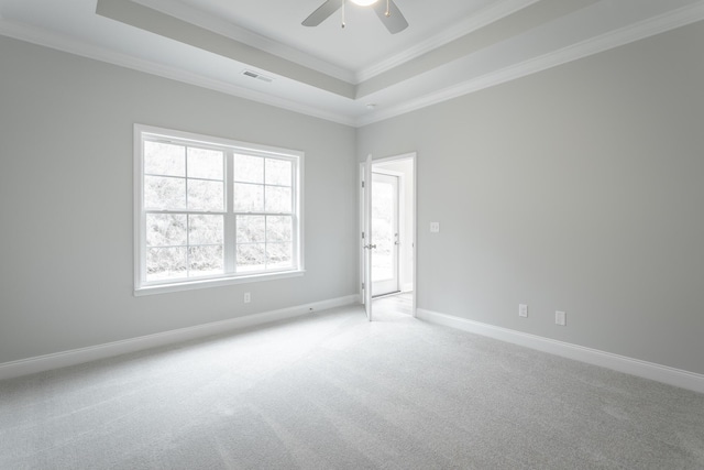 spare room featuring baseboards, ornamental molding, a ceiling fan, a tray ceiling, and light colored carpet