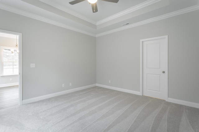 spare room with baseboards, a raised ceiling, ornamental molding, carpet floors, and ceiling fan with notable chandelier