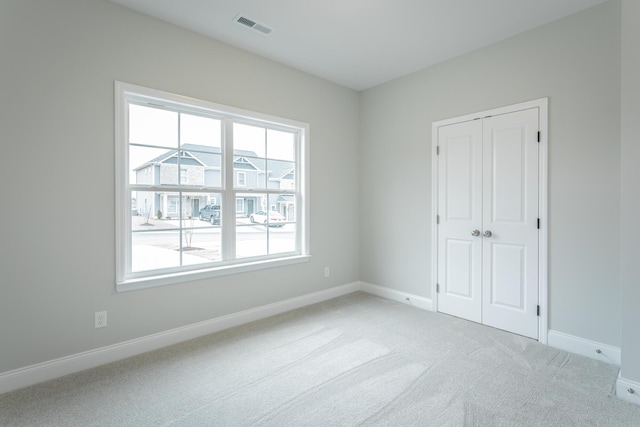 unfurnished room with light colored carpet, baseboards, and visible vents