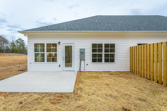 rear view of house featuring roof with shingles, a patio, and fence