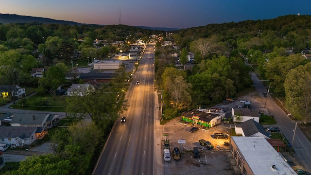 aerial view at dusk featuring a wooded view