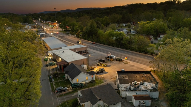 aerial view at dusk featuring a wooded view