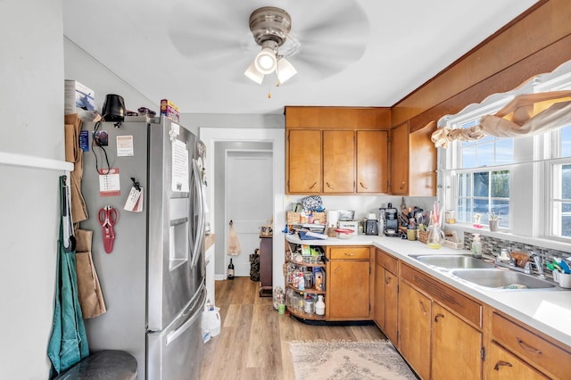 kitchen with a sink, light wood-type flooring, stainless steel fridge, ceiling fan, and light countertops