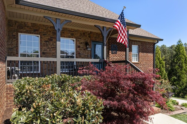 12237 Wildlife Pl, Soddy Daisy, TN 37379 - view of side of home with stone siding, covered porch, roof with shingles, and brick siding