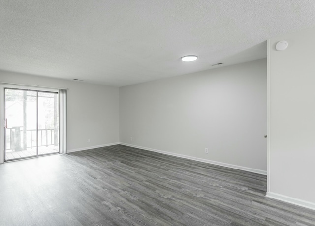empty room featuring baseboards, visible vents, a textured ceiling, and dark wood-style floors