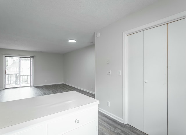 interior space featuring wood finished floors, a textured ceiling, and baseboards