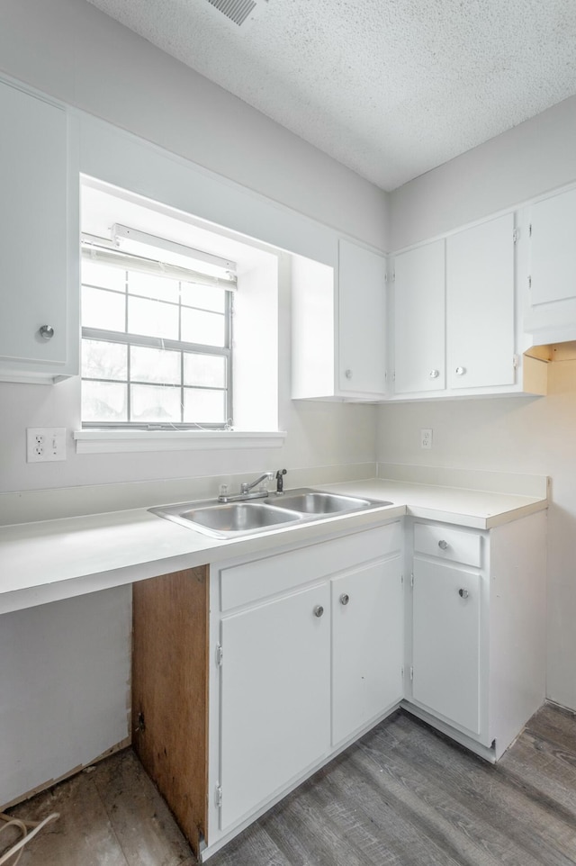 kitchen with white cabinets, light countertops, light wood-style flooring, and a textured ceiling