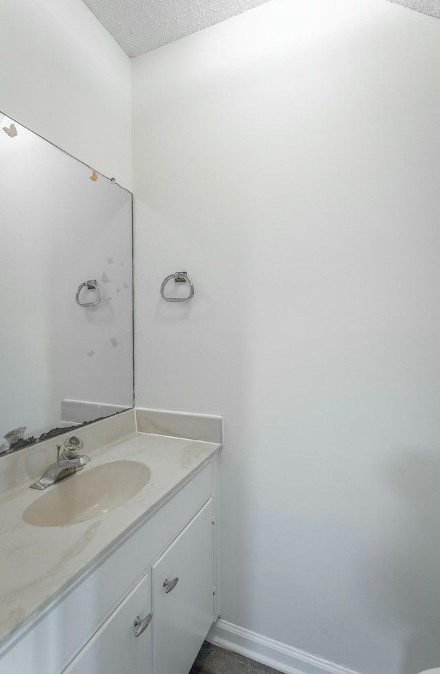 bathroom with baseboards, vanity, and a textured ceiling