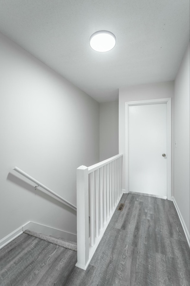 staircase with wood finished floors, visible vents, and baseboards