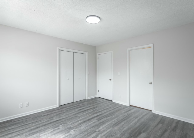 unfurnished bedroom featuring a closet, wood finished floors, a textured ceiling, and baseboards