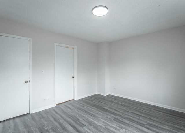 unfurnished bedroom featuring baseboards, a textured ceiling, and dark wood-type flooring