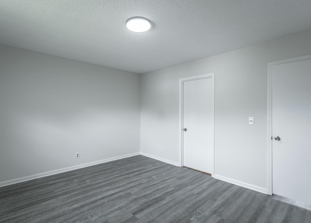 spare room with baseboards, a textured ceiling, and dark wood-style floors