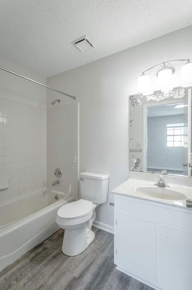 bathroom featuring a textured ceiling, toilet, visible vents, wood finished floors, and vanity
