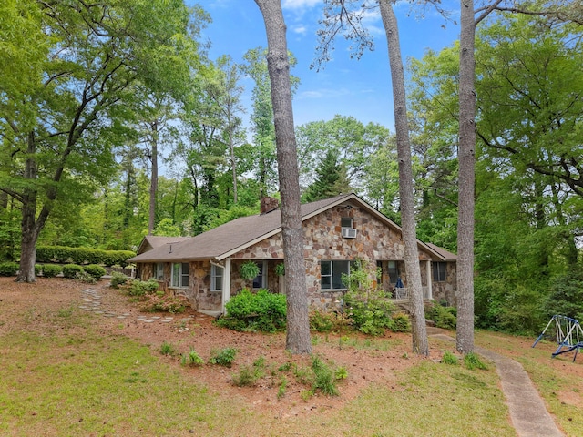 view of front of home with a chimney, stone siding, and a playground