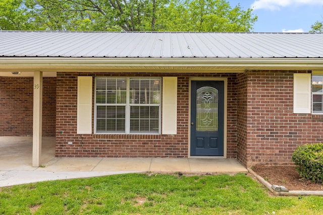 doorway to property featuring metal roof and brick siding