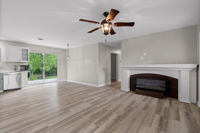 unfurnished living room with a fireplace, ceiling fan, light wood-type flooring, and baseboards