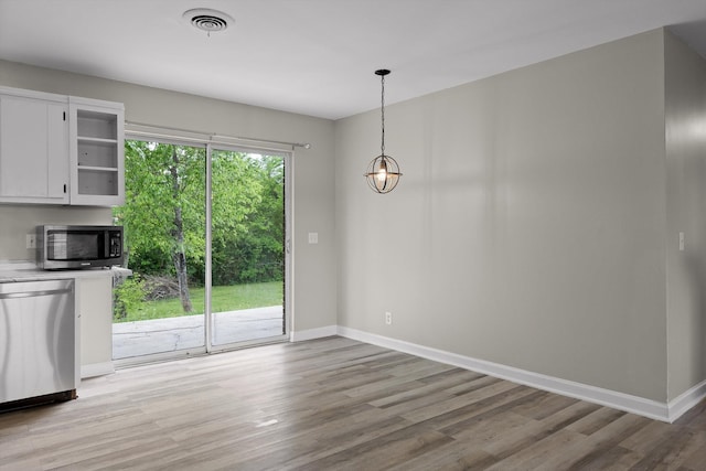 unfurnished dining area with light wood finished floors, visible vents, a chandelier, and baseboards