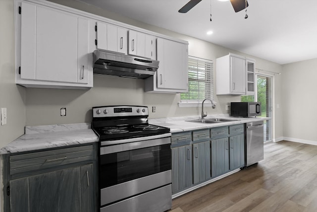 kitchen with light wood finished floors, a sink, under cabinet range hood, ceiling fan, and appliances with stainless steel finishes
