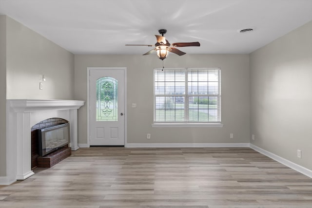 entryway with ceiling fan, baseboards, light wood-style flooring, and a fireplace