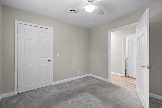 carpeted empty room with ceiling fan, visible vents, and baseboards