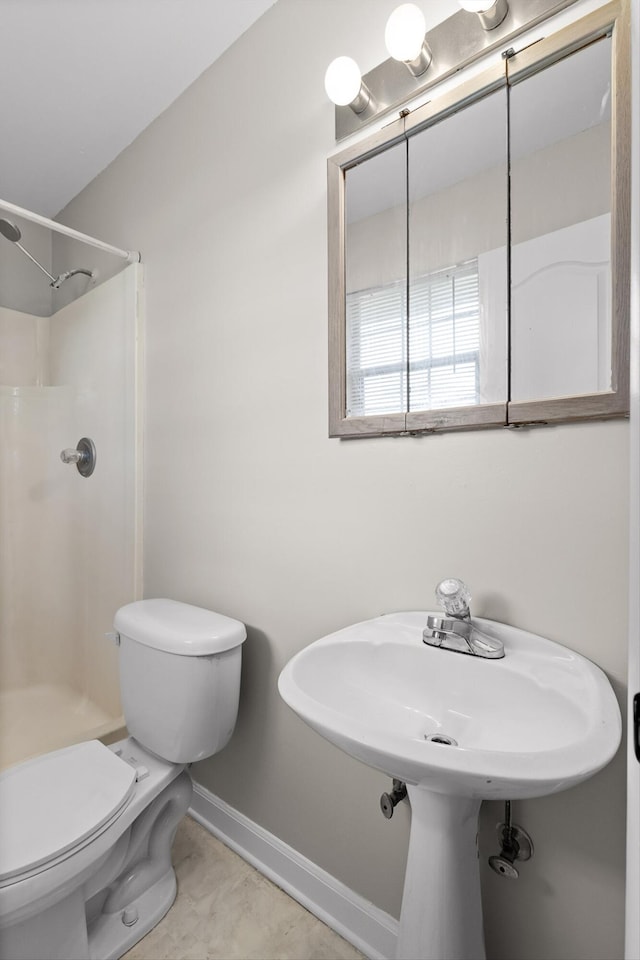 bathroom featuring walk in shower, toilet, and baseboards