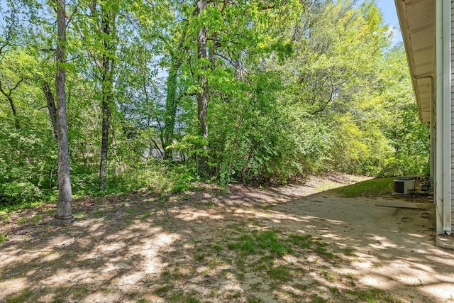 view of yard with a wooded view and central AC unit