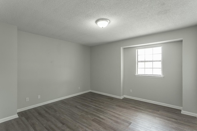spare room with dark wood finished floors, a textured ceiling, and baseboards
