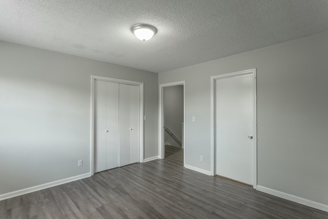 unfurnished bedroom with baseboards, a textured ceiling, dark wood-style floors, and a closet