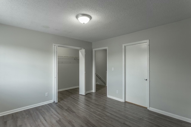 unfurnished bedroom featuring baseboards, dark wood-type flooring, and a textured ceiling