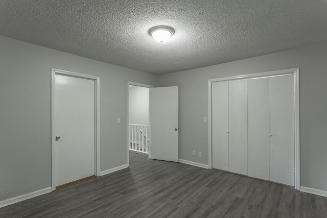 unfurnished bedroom featuring a closet, wood finished floors, a textured ceiling, and baseboards
