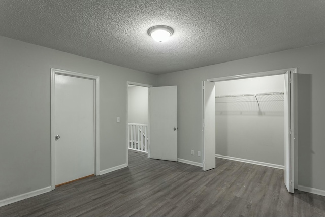 unfurnished bedroom with dark wood finished floors, baseboards, a textured ceiling, and a closet