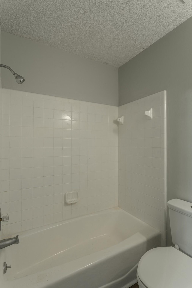 full bathroom featuring a textured ceiling, toilet, and bathing tub / shower combination