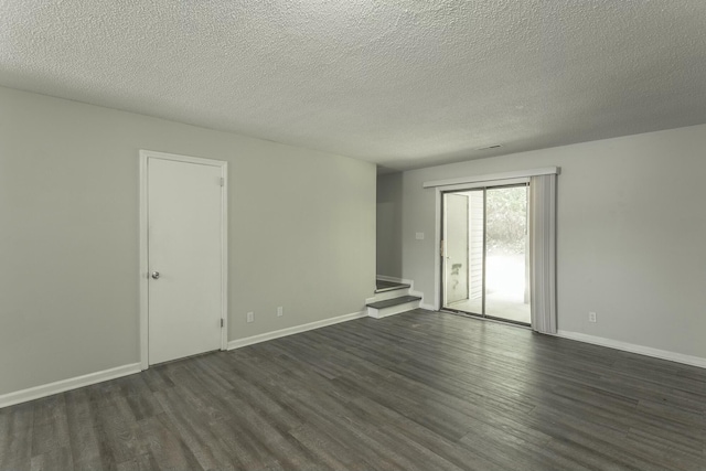 spare room featuring baseboards, dark wood-style floors, a textured ceiling, and stairway