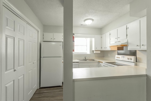 kitchen featuring a textured ceiling, white appliances, light countertops, under cabinet range hood, and visible vents
