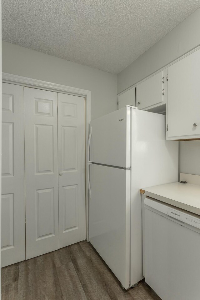 kitchen featuring a textured ceiling, white appliances, light countertops, white cabinets, and dark wood-style floors