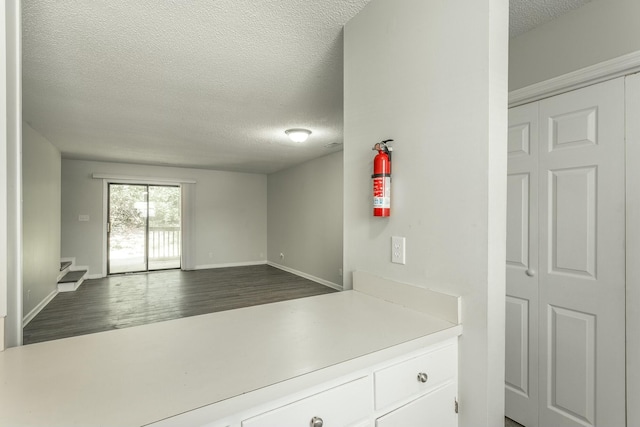 kitchen featuring white cabinets, dark wood finished floors, light countertops, baseboards, and a textured ceiling