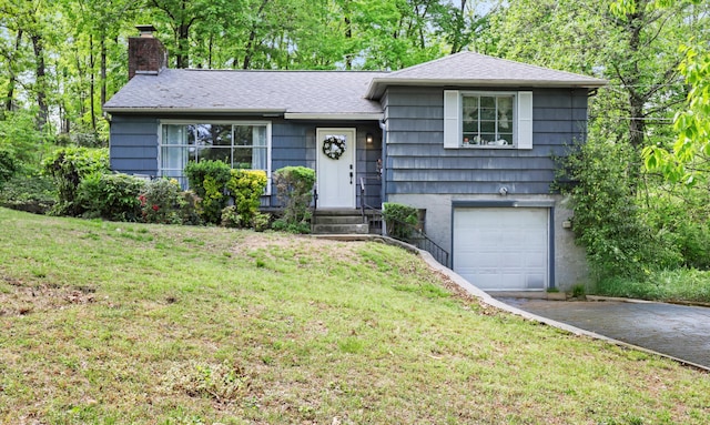 split level home with an attached garage, a chimney, a front lawn, and aphalt driveway