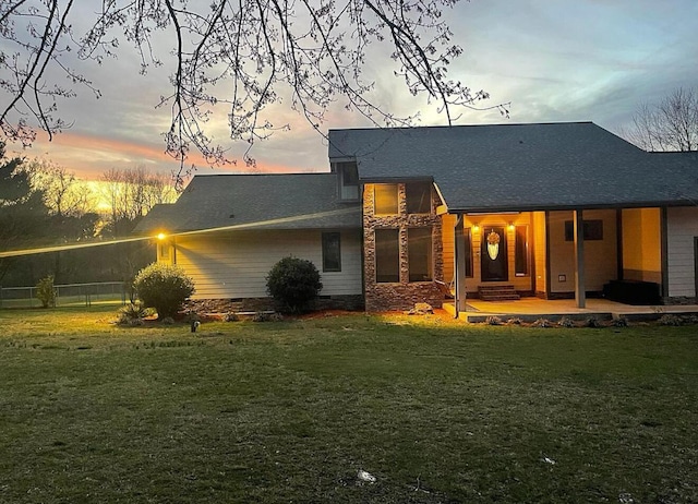 back of property at dusk featuring a yard and crawl space
